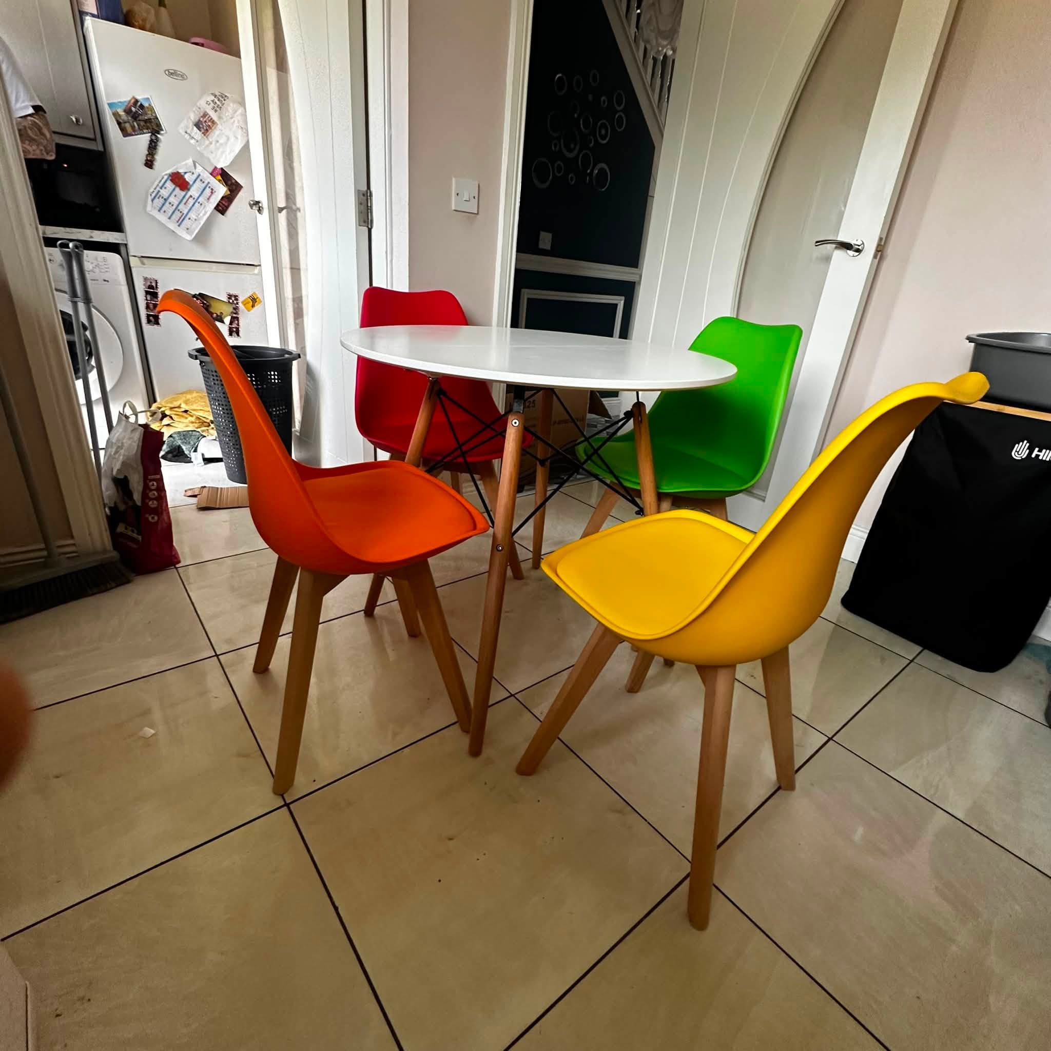 Round dining table and four coloured chairs assembled in a kitchen